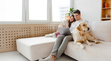 Portrait,Of,Happy,Young,Couple,Using,Laptop,,Man,Holding,Mobile